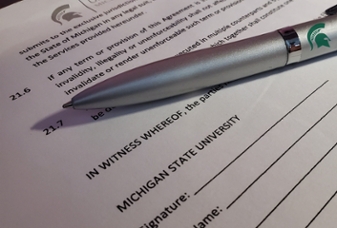 A silver pen sitting on top of an empty contract