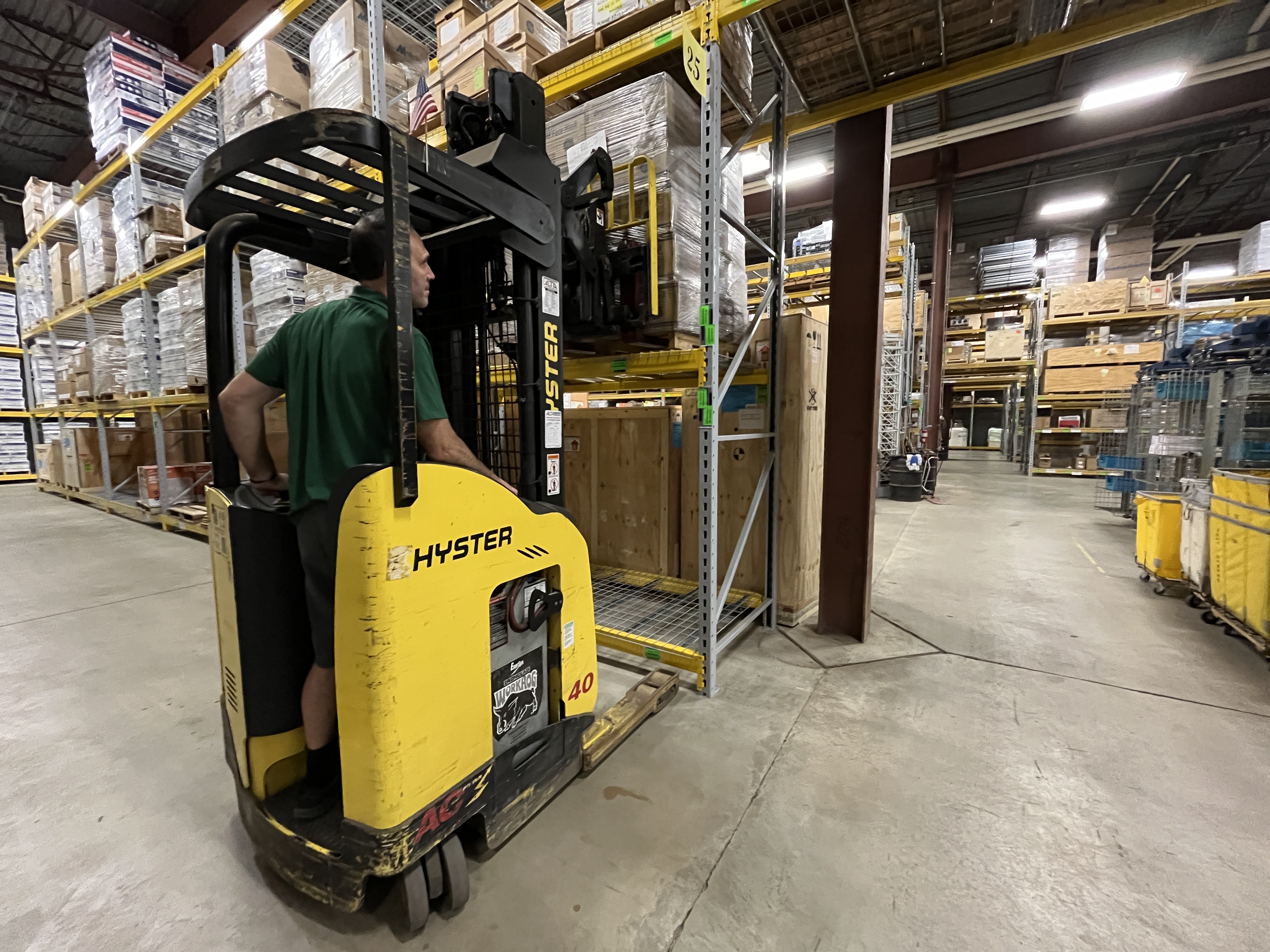 A UPL warehouse employee in a yellow forklift storing a pallet of items inside the UPL warehouse. 
